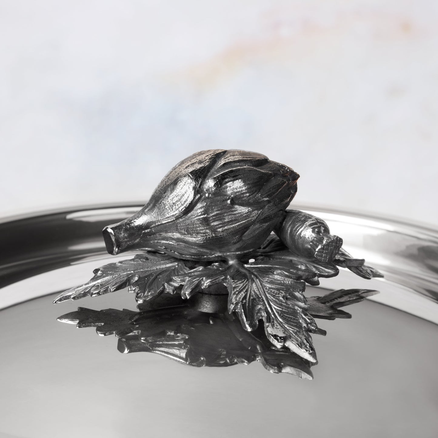Decorated knob finial representing artichoke and carrot, cast in solid bronze and silver plated, on Opus Prima stainless steel lid by Ruffoni