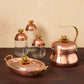 lotus 5 piece set including a copper tea kettle, copper 10" roaster and a set of 3 kitchen glass jars in glass and copper, all topped by lotus-shaped bronze knobs