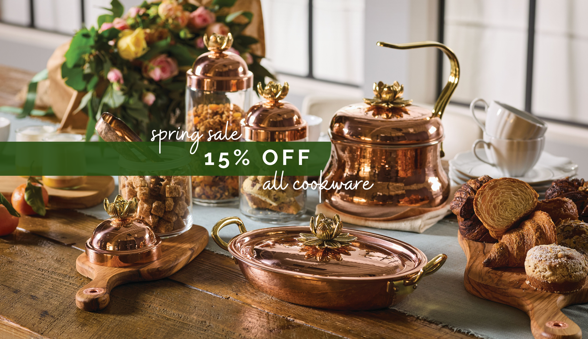 Copper cookware on a table with a spring sale banner.