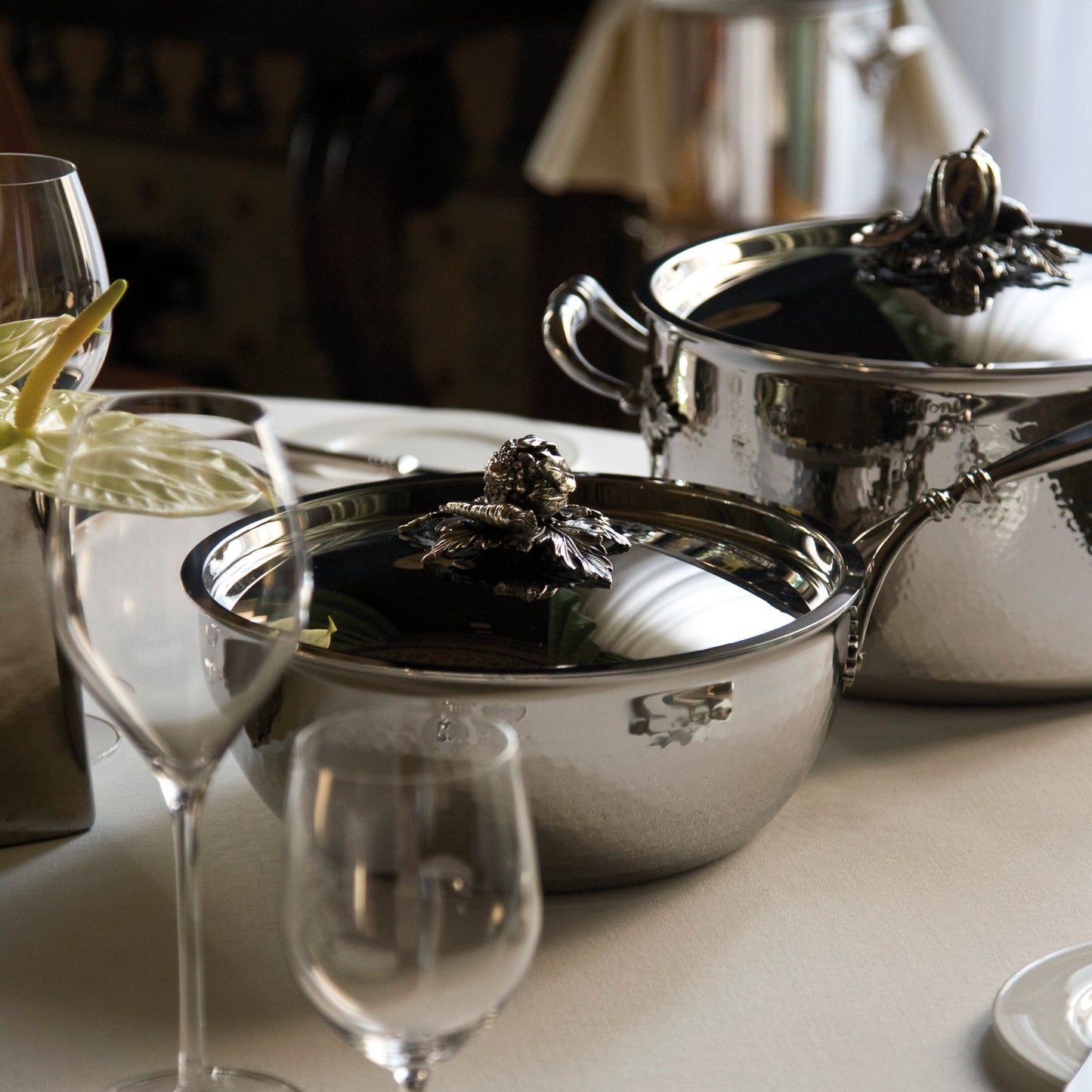 Opus Prima hammered clad stainless steel chefs pan with decorated silver-plated lid knob finial from Ruffoni on a classic tablesetting