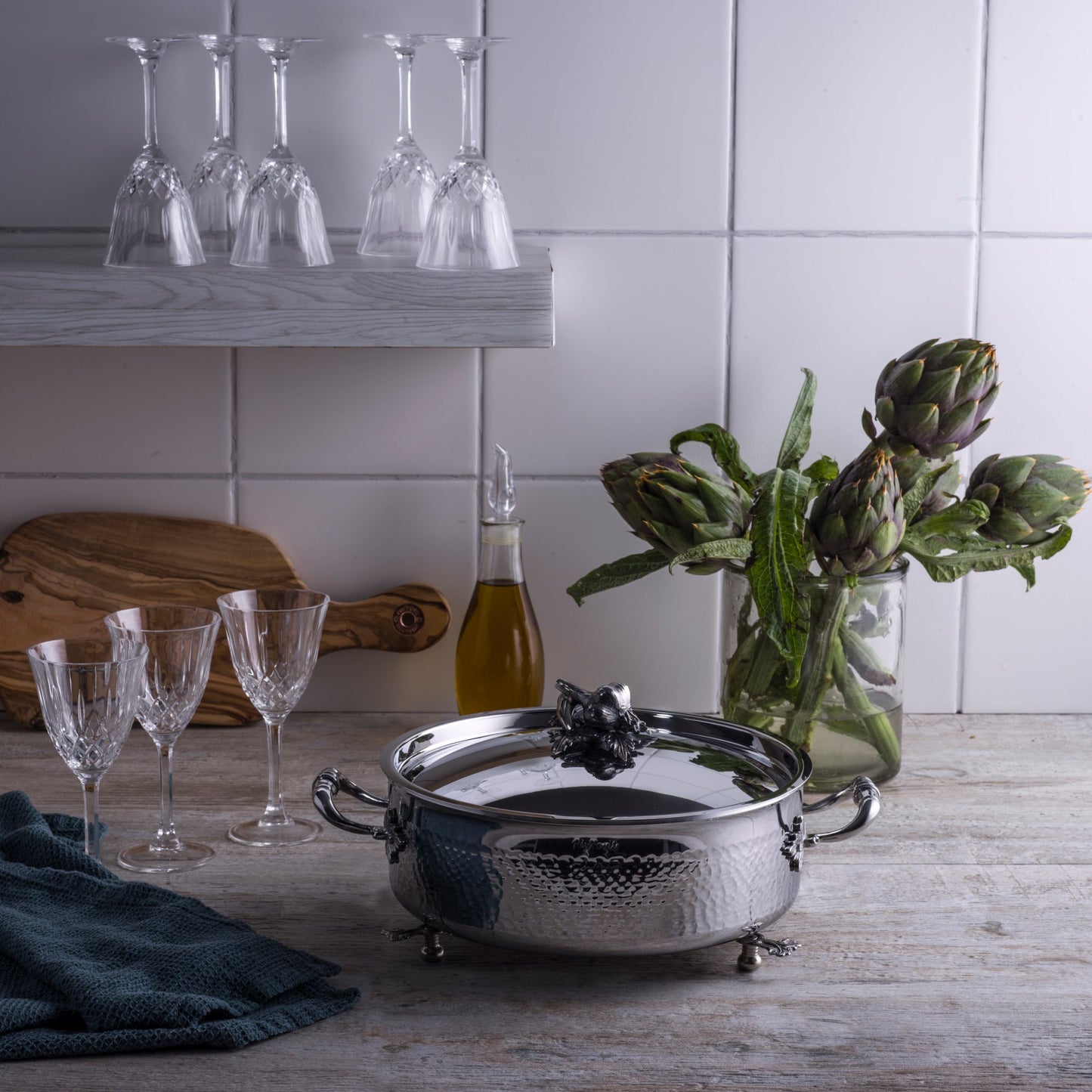 Opus Prima hammered clad stainless steel braiser with decorated silver-plated lid knob finial from Ruffoni in an Italian kitchen with glass and artichokes