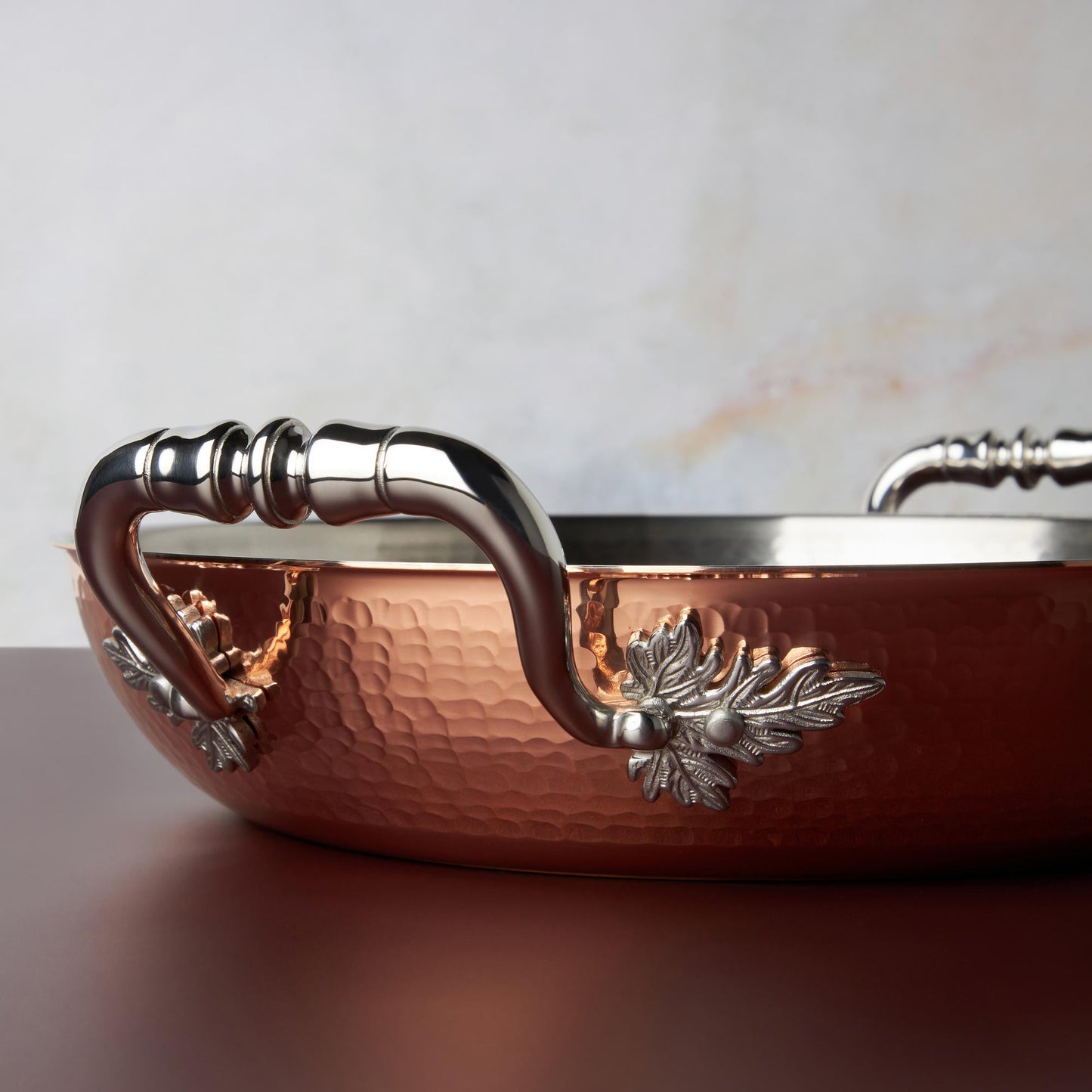 Beautiful stainless steel handle decorated with delicate leaves on Opus Cupra cookware by Ruffoni